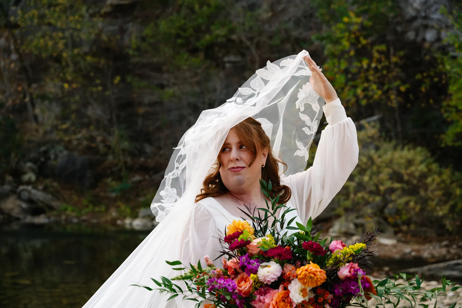 Bride holding her veil and bouquet during an elopement at the Buffalo National River in Arkansas.