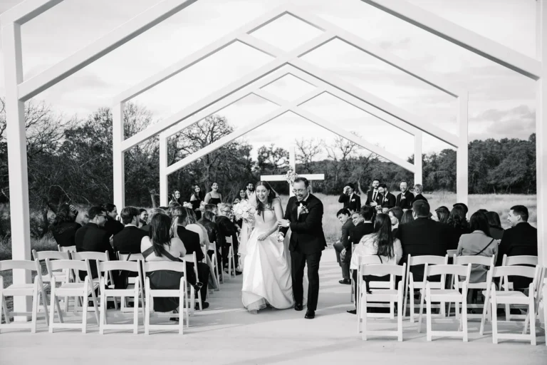 Couple walking down the aisle together after their outdoor wedding ceremony at Swallows Eve in Texas as guests celebrate.