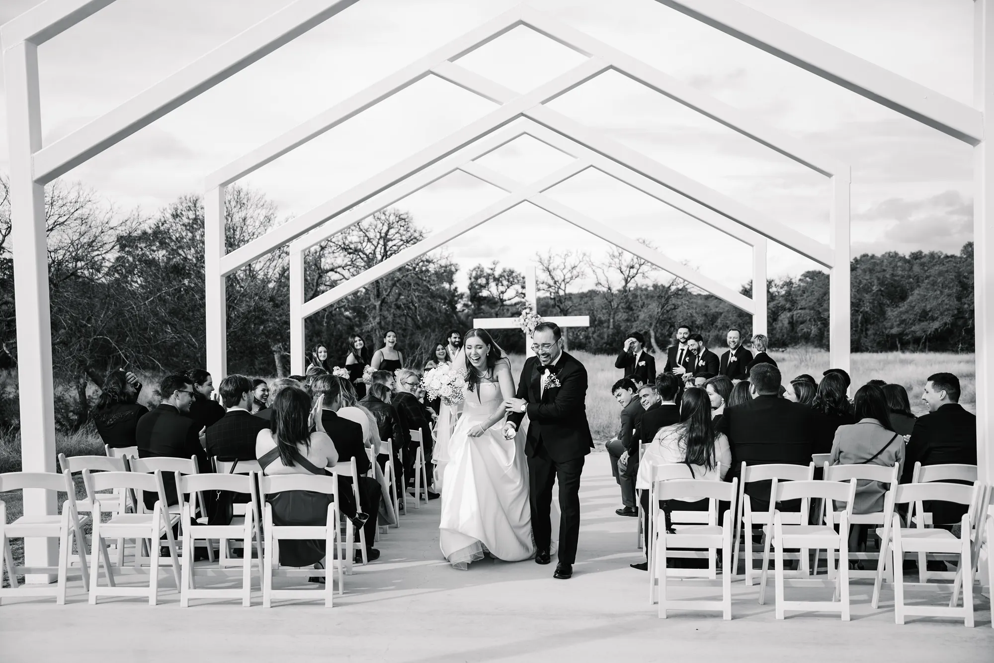 Couple walking down the aisle together after their outdoor wedding ceremony at Swallows Eve in Texas as guests celebrate.
