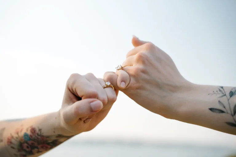 Close-up of Darcy and Kassidy holding hands and showing their wedding rings during their queer elopement at the Dallas Arboretum