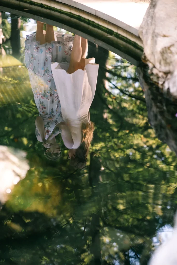 Reflection of Darcy and Kassidy in water during their queer elopement at the Dallas Arboretum.
