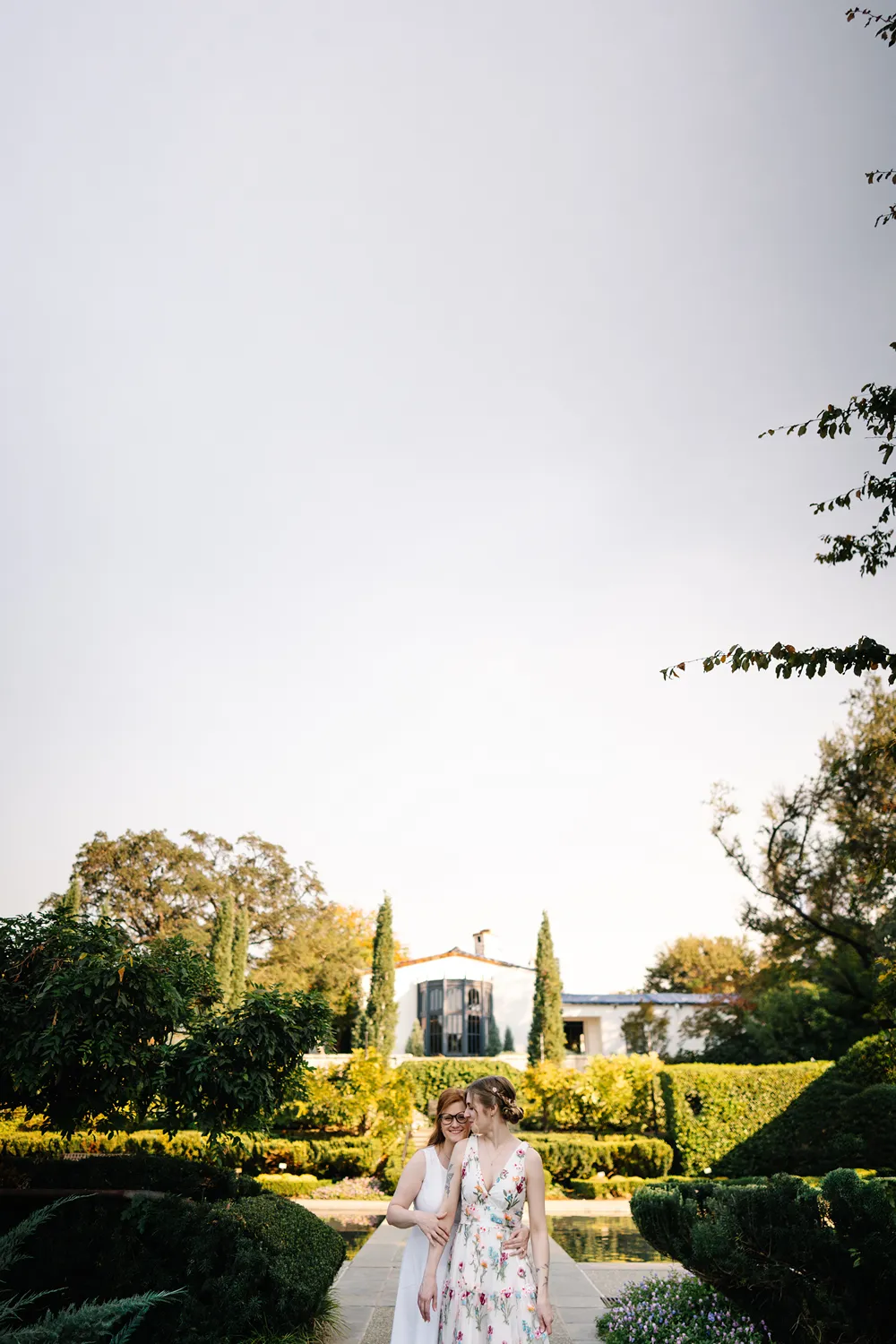 Darcy and Kassidy walking together during their queer elopement at the Dallas Arboretum.