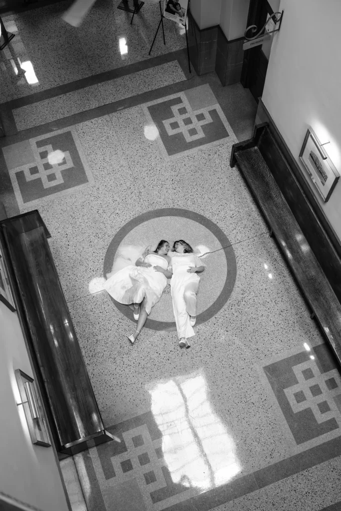 Overhead view of a queer LGBTQ couple lying together inside the Fort Worth courthouse after their elopement ceremony.