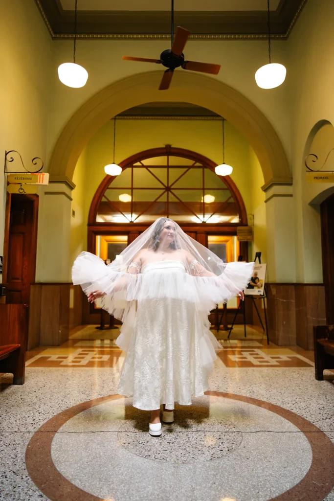Queer LGBTQ bride posing with veil inside the Fort Worth courthouse during an intimate elopement.