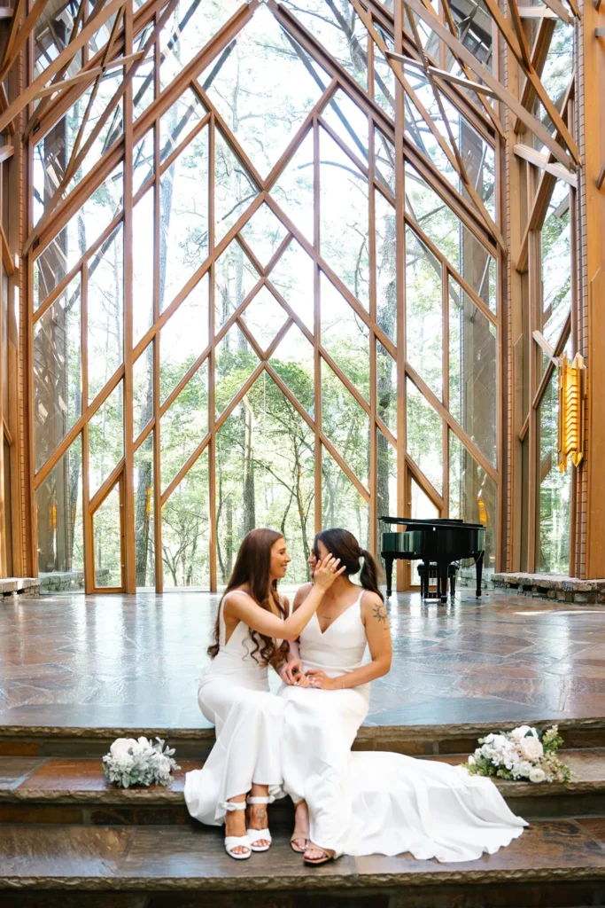 Brook and Hannah sitting together inside Anthony Chapel at Garvan Woodland Gardens during their queer wedding in Hot Springs, Arkansas.