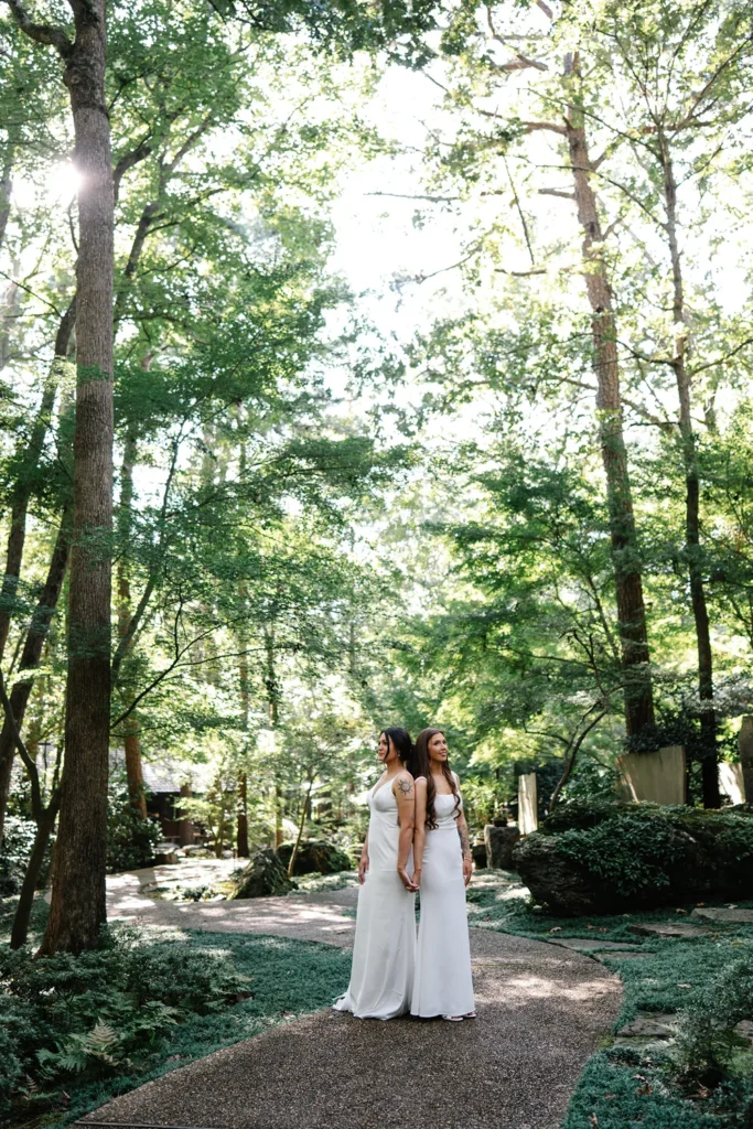 Brook and Hannah holding hands in Garvan Woodland Gardens after their queer wedding in Hot Springs, Arkansas.